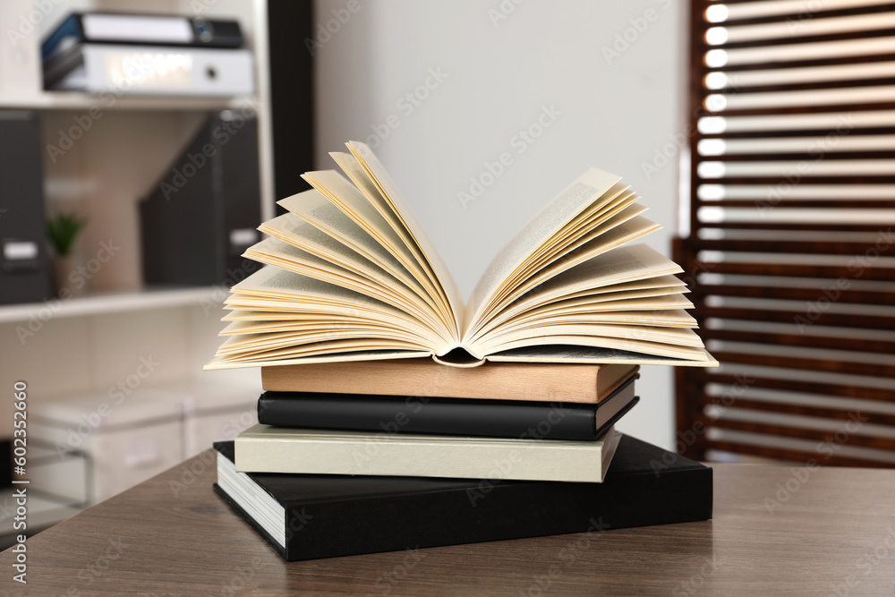 Stack of different hardcover books on wooden table indoors Stack of different hardcover books on wooden table indoors