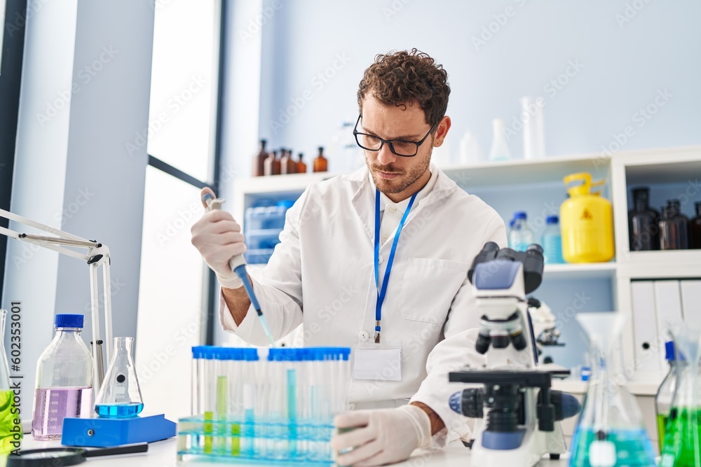 Young hispanic man scientist pouring liquid on test tubes at laboratory Young hispanic man scientist pouring liquid on test tubes at laboratory
