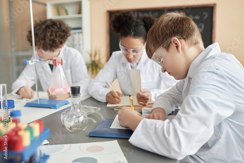 Side view portrait of schoolboy in science class with group of children, copy space