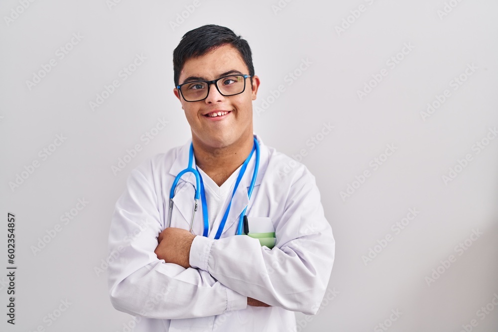 Young hispanic man with down syndrome wearing doctor uniform and stethoscope happy face smiling with crossed arms looking at the camera. positive person. Young hispanic man with down syndrome wearing doctor uniform and stethoscope happy face smiling with crossed arms looking at the camera. positive person.