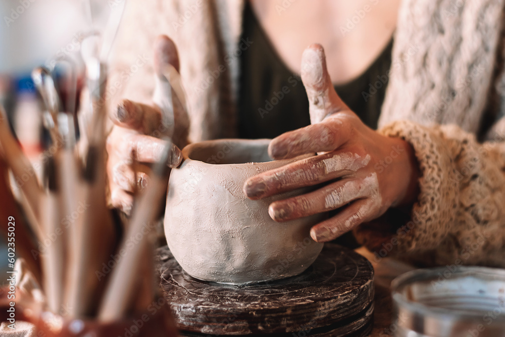 Female sculptor making clay mug in a home workshop,hands close-up.Small business,entrepreneurship,hobby, leisure concept.