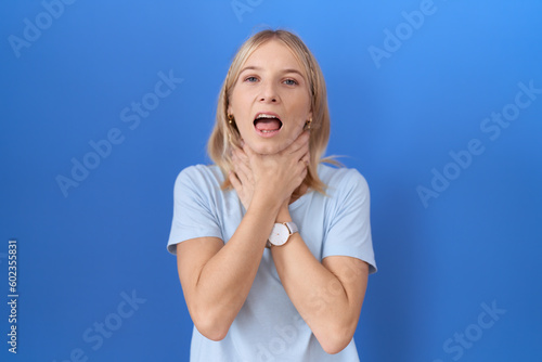 Young caucasian woman wearing casual blue t shirt shouting suffocate because painful strangle. health problem. asphyxiate and suicide concept.