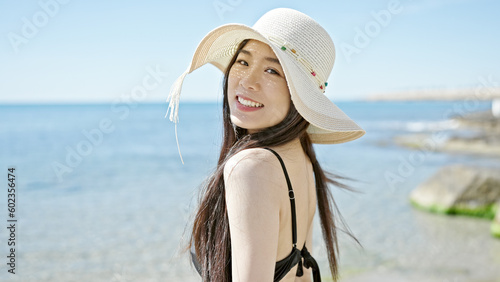 Obraz na plátně Young chinese woman tourist smiling confident wearing swimsuit and summer hat at