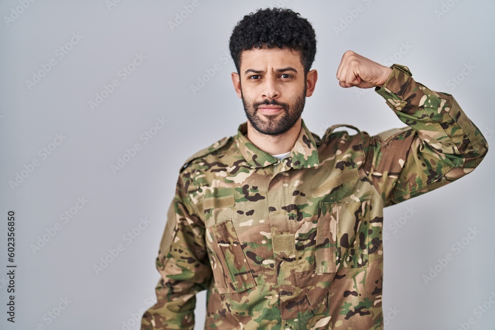 Arab man wearing camouflage army uniform strong person showing arm muscle, confident and proud of power