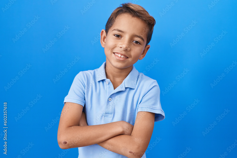 Little hispanic boy wearing casual blue t shirt happy face smiling with crossed arms looking at the camera. positive person. Little hispanic boy wearing casual blue t shirt happy face smiling with crossed arms looking at the camera. positive person.