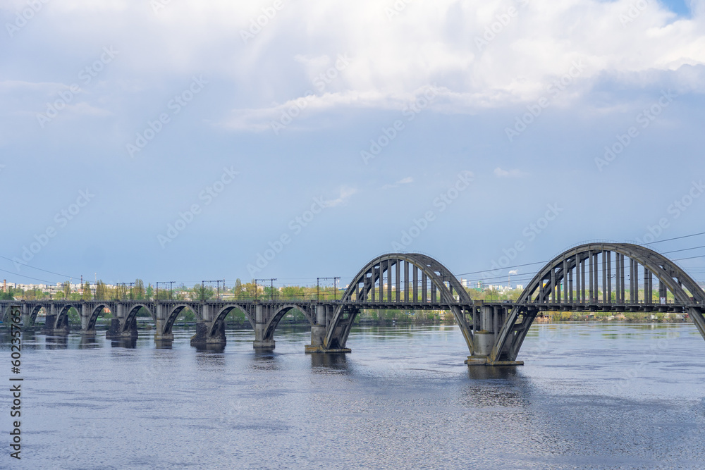 View of river Dnepr and railway ancient arched bridge. Unique construction across wide water 19th century. Railway line along the Merefo-Kherson bridge. Panoramic on modern city and spring landscape.