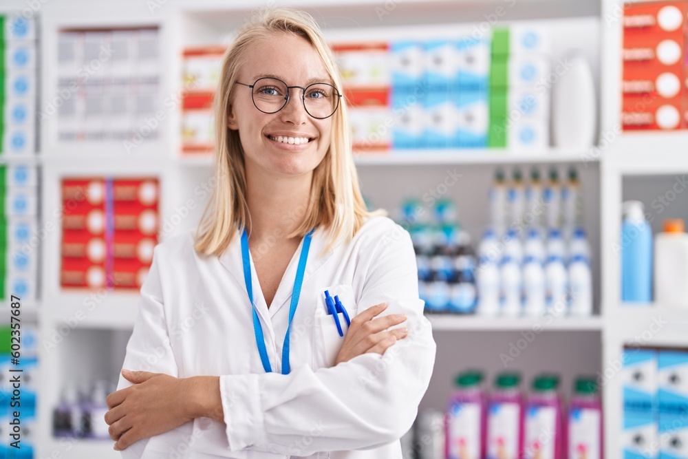Young blonde woman pharmacist smiling confident standing with arms crossed gesture at pharmacy Young blonde woman pharmacist smiling confident standing with arms crossed gesture at pharmacy