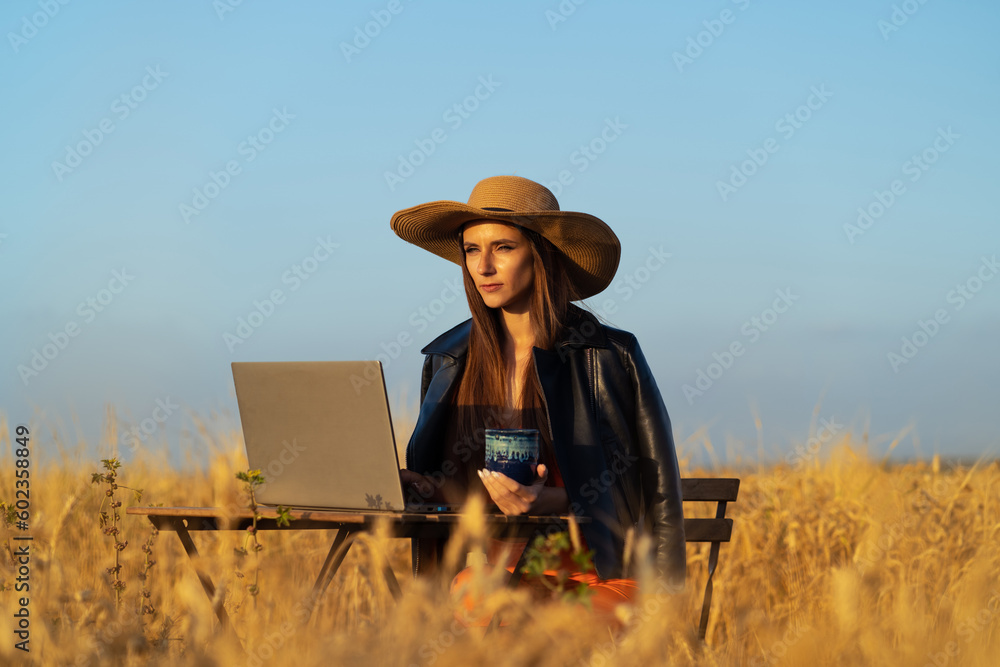 A digital nomad ponders while working on a laptop in a wheat field A digital nomad ponders while working on a laptop in a wheat field