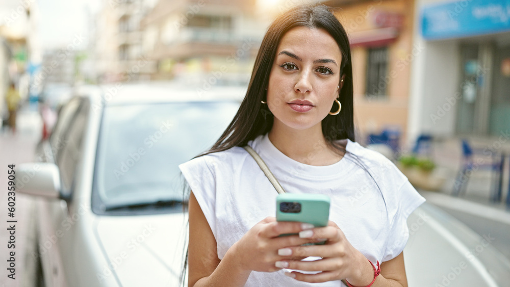 Young beautiful hispanic woman using smartphone standing by car at street Young beautiful hispanic woman using smartphone standing by car at street