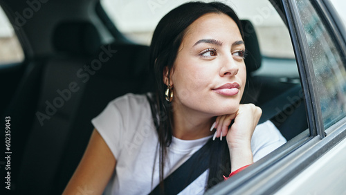 Young beautiful hispanic woman passenger sitting on car with relaxed expression at street © Krakenimages.com