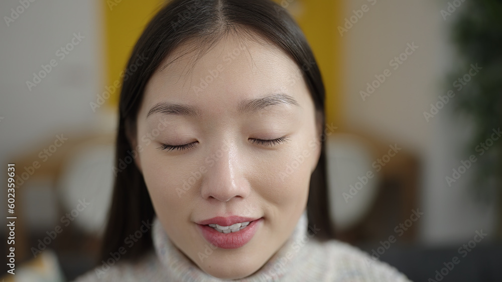 Young chinese woman sitting on sofa breathing at home Young chinese woman sitting on sofa breathing at home