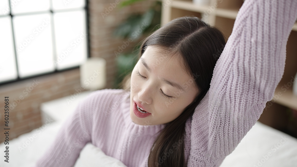 Young chinese woman waking up stretching arms at bedroom Young chinese woman waking up stretching arms at bedroom