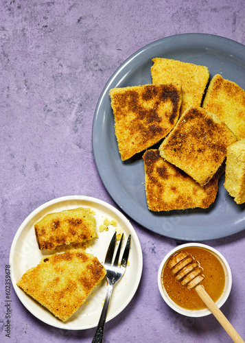 hands eating a harcha or mbasses semolina algerian pancakes on an arabesque colorful plate above cutting board. Traditional algerian breakfast bread with honey bowl photo