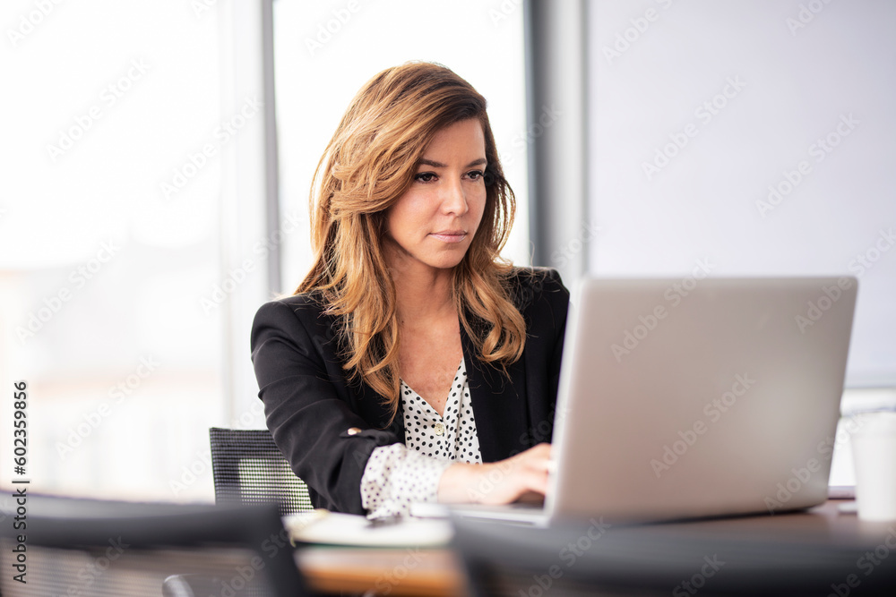 Shot of a business woman using laptop and working in a modern glass office Shot of a business woman using laptop and working in a modern glass office