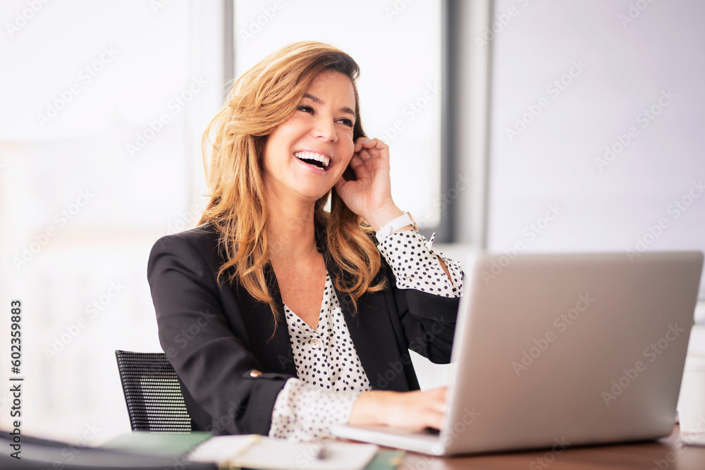 Shot of a happy business woman using laptop and working in a modern glass office Shot of a happy business woman using laptop and working in a modern glass office