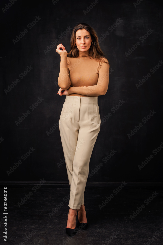Confident woman full length shot at isolated dark background Confident woman full length shot at isolated dark background