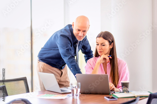 Businesswoman and businessman using laptops and working together at the office