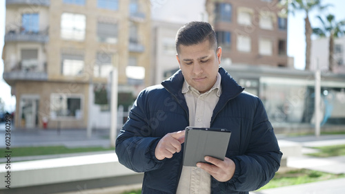 Young hispanic man using touchpad at street