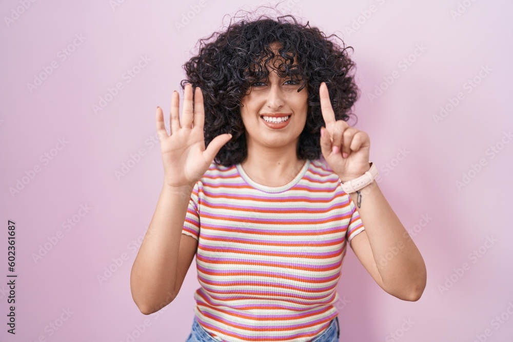 Young middle east woman standing over pink background showing and pointing up with fingers number six while smiling confident and happy. Young middle east woman standing over pink background showing and pointing up with fingers number six while smiling confident and happy.