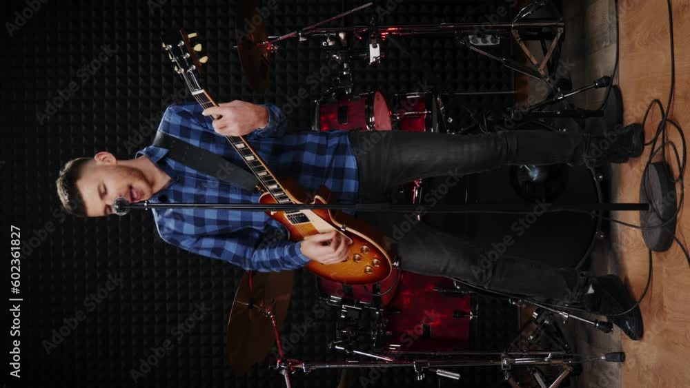 Male musician performing song on guitar at rehearsal studio. Vertical video Male musician performing song on guitar at rehearsal studio. Vertical video