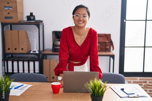 Fotografie Young chinese woman business worker smiling confident standing by desk at office