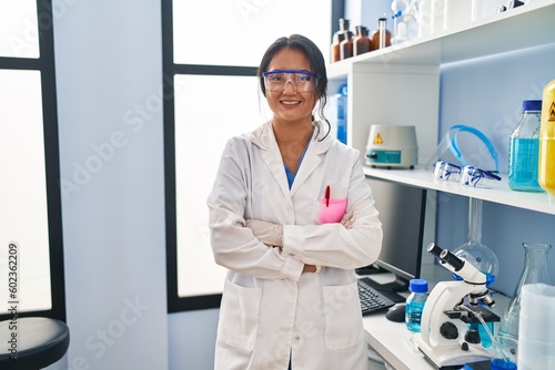 Young chinese woman wearing scientist uniform standing with arms crossed gesture at laboratory