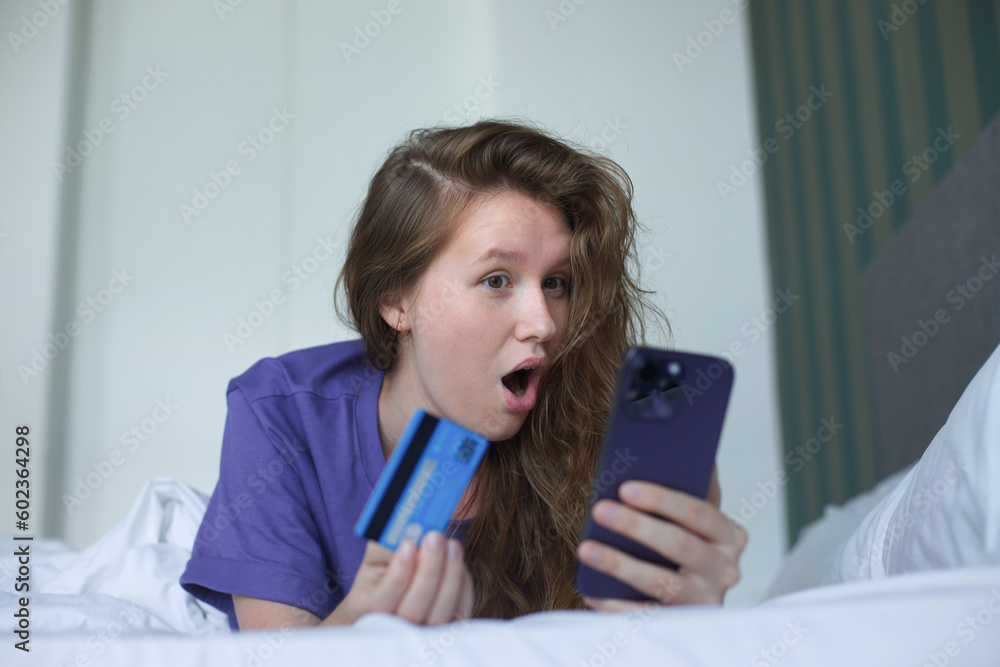 young woman with credit bank card and cell mobile phone, smartphone at home in living room young woman with credit bank card and cell mobile phone, smartphone at home in living room