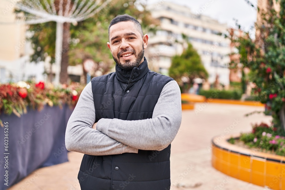 Fototapeta premium Young latin man standing with arms crossed gesture at park