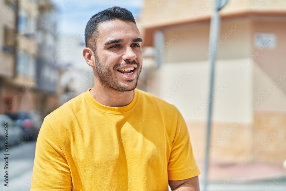 Young hispanic man smiling confident looking to the side at street