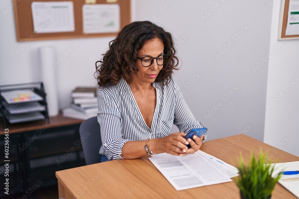Middle age woman business worker using smartphone working at office Middle age woman business worker using smartphone working at office