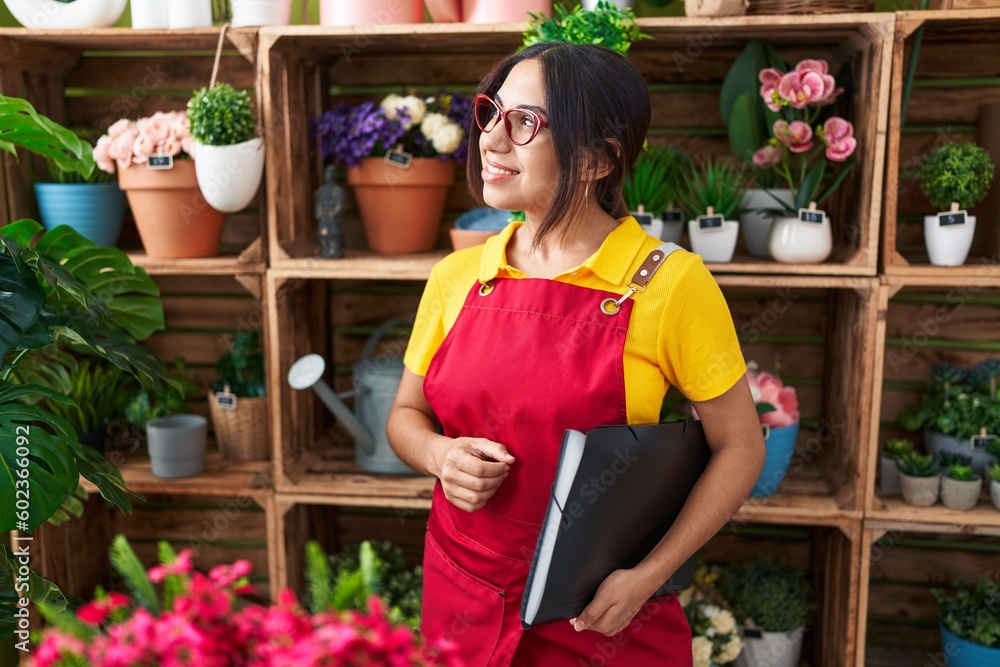 Young beautiful arab woman florist smiling confident holding binder at flower shop