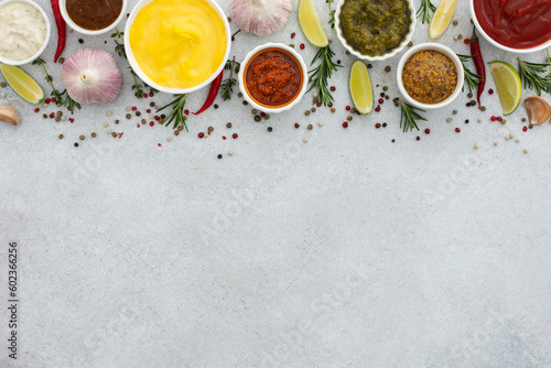 Different types of sauces in bowls with seasonings, rosemary and pepper, thyme and garlic, lime and lemon, cilantro, top view, copy space