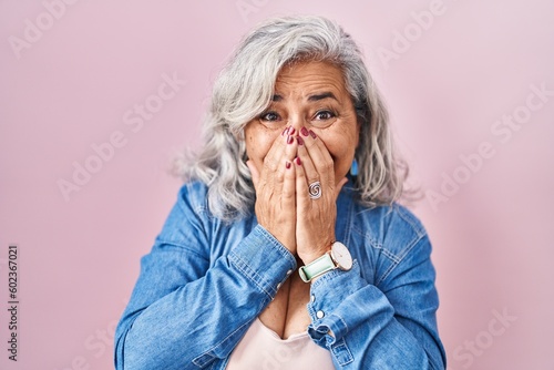 фотографія Middle age woman with grey hair standing over pink background laughing and embar