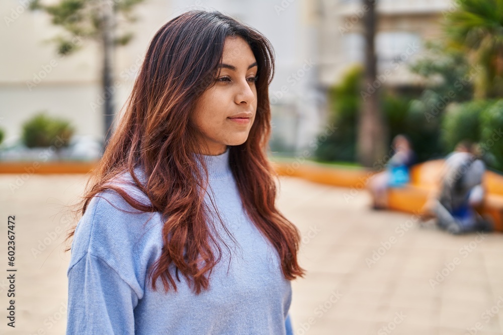 Young hispanic woman with relaxed expression standing at park