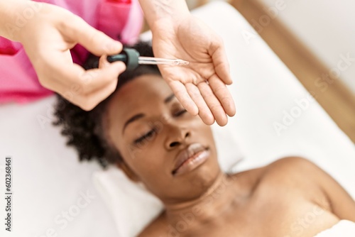 African american woman lying on massage table having facial treatment at beauty salon