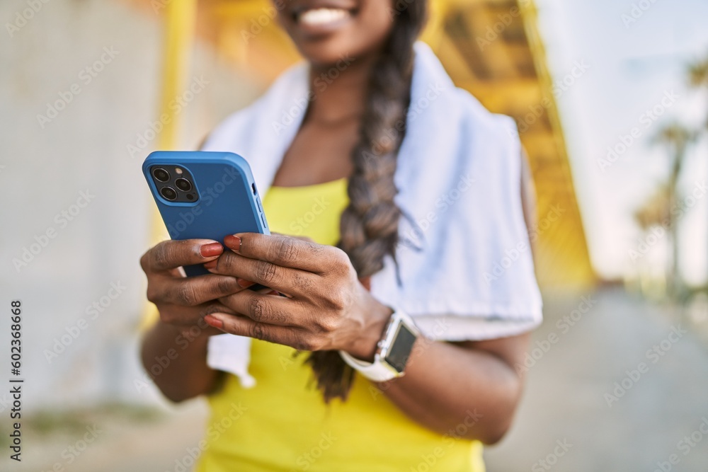 African american woman wearing sportswear using smartphone at street
