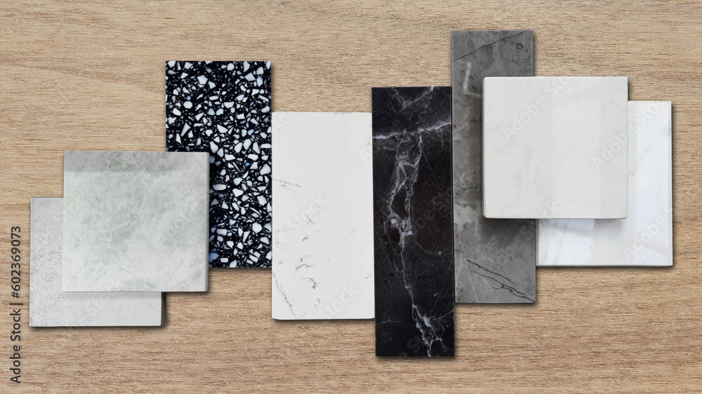 close up of interior premium stone samples including black marble, grey artificial stone, terrazzo tiles placed with floor tiles. counter top samples on wooden table background. close up of interior premium stone samples including black marble, grey artificial stone, terrazzo tiles placed with floor tiles. counter top samples on wooden table background.