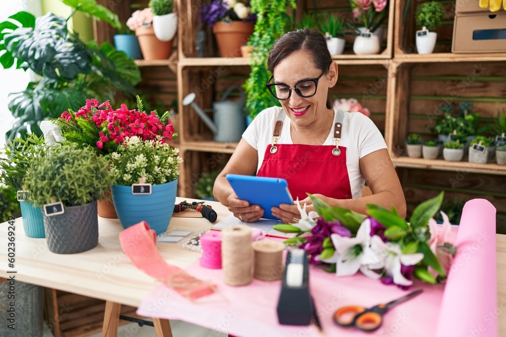 Young beautiful hispanic woman florist smiling confident using touchpad at flower shop Young beautiful hispanic woman florist smiling confident using touchpad at flower shop