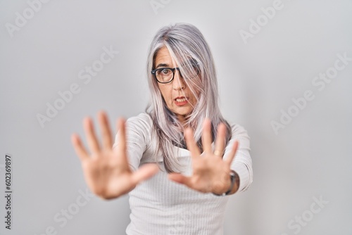 Wallpaper Mural Middle age woman with grey hair standing over white background afraid and terrified with fear expression stop gesture with hands, shouting in shock. panic concept. Torontodigital.ca