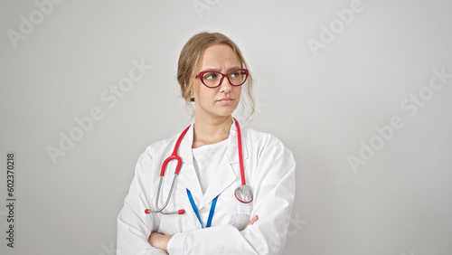Young blonde woman doctor standing with serious expression and arms crossed gesture over isolated white background