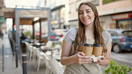Young beautiful hispanic woman waitress smiling confident holding take away coffee at coffee shop terrace