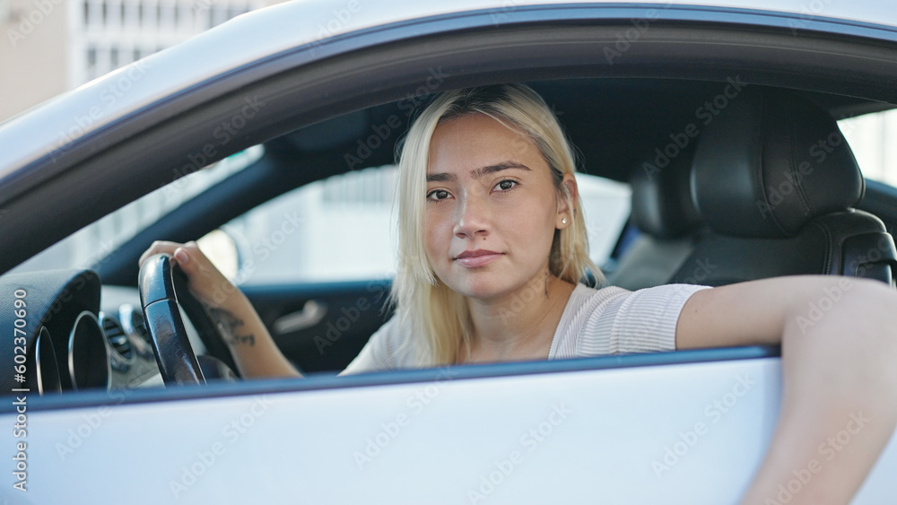 Young beautiful hispanic woman sitting on car with relaxed expression at street