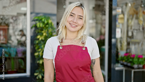 Young beautiful hispanic woman smiling confident wearing apron at flower shop