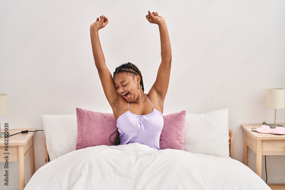 African american woman waking up stretching arms yawning at bedroom African american woman waking up stretching arms yawning at bedroom