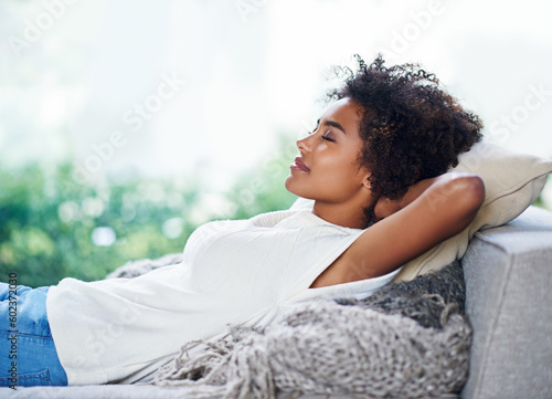 Relax, sleep and woman on sofa in living room, afternoon nap and calm weekend rest in apartment. Sleeping, daydream and peace, girl on couch relaxing, self care and stress free chill time in lounge. photo