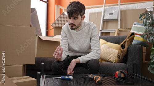 Young hispanic man stressed assembling new table at new home