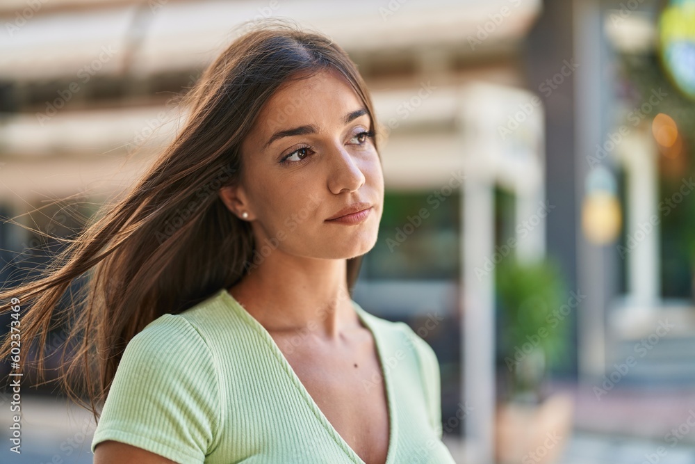 Young beautiful hispanic woman standing with serious expression at street