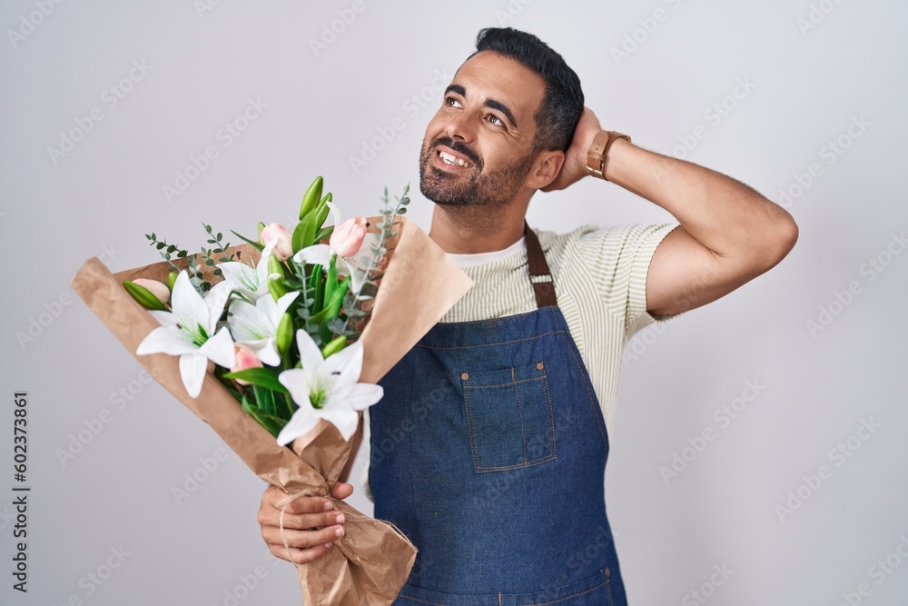 Hispanic man with beard working as florist smiling confident touching hair with hand up gesture, posing attractive and fashionable