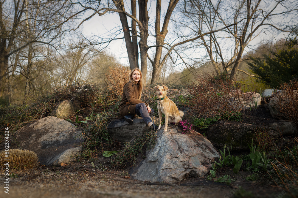 Beautiful blonde girl with dog walking in the park