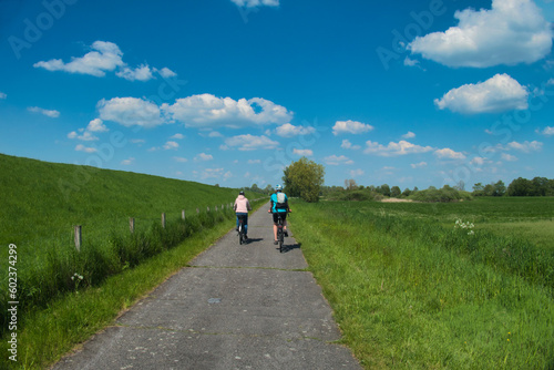 Radfahrer auf dem Weg von Papenburg nach Leer im Fr  hjahr. Aufnahme aus dem Fr  hjahr mit Blick in die Weite des Emslandes und auf den Deich der Ems in Norddeutschland